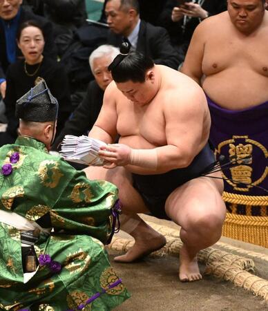 豊昇龍を寄り切りで破り、懸賞の束を手にする義ノ富士＝１３日