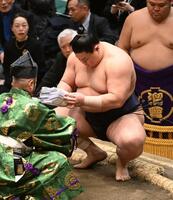 豊昇龍を寄り切りで破り、懸賞の束を手にする義ノ富士＝１３日