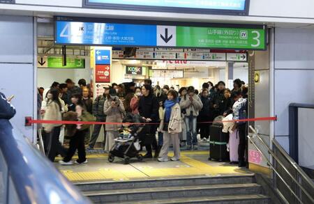 　ホームへ下りる階段に張られた規制線の前で運転再開を待つ人々（撮影・伊藤笙子）