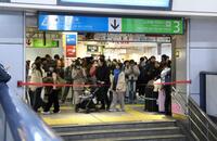 　ホームへ下りる階段に張られた規制線の前で運転再開を待つ人々（撮影・伊藤笙子）