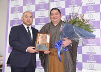 引退会見で志賀ノ浦親方（左）から贈呈された花束と恩師で鹿児島商業高校相撲部元監督の禧久昭広さんの遺影を手に笑顔を見せる大奄美（撮影・開出牧）