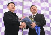定年前会見で湊川親方（元貴景勝）から花束を受け取り握手を交わす常磐山親方（右）＝撮影・開出牧
