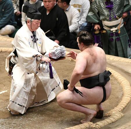 分厚い懸賞の束を受け取る安青錦（撮影・佐藤厚）