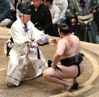 分厚い懸賞の束を受け取る安青錦（撮影・佐藤厚）