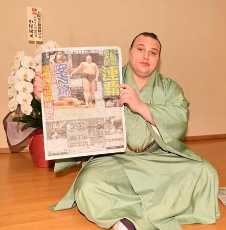 連覇を報じるデイリースポーツを手にポーズをとる安青錦（撮影・開出牧）