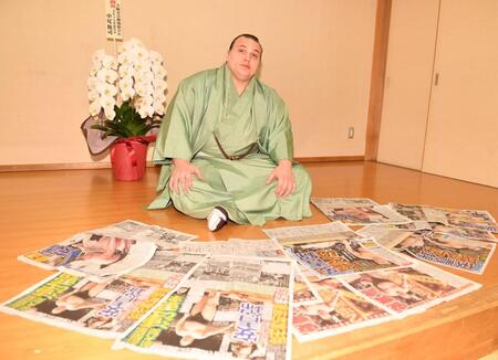 連覇を報じるスポーツ新聞各紙を並べポーズをとる安青錦（撮影・開出牧）