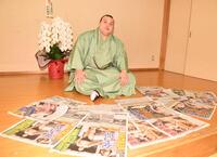 連覇を報じるスポーツ新聞各紙を並べポーズをとる安青錦（撮影・開出牧）