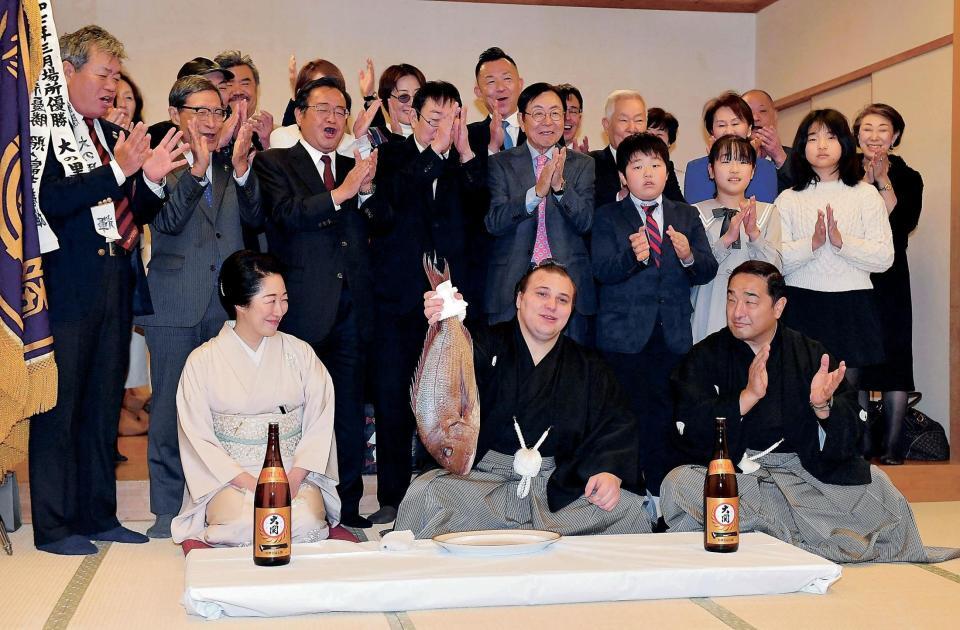 連覇を果たし鯛を手に会心の笑みを浮かべる安青錦（中央）。右は安治川親方、左は安治川部屋の女将・杉野森絵莉さん＝１月２５日