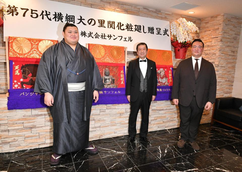 新しい不動明王の化粧まわしと（左から）大の里、深澤朝房社長、二所ノ関親方（撮影・持木克友）