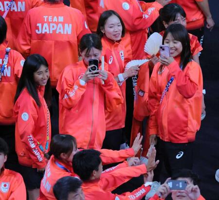 パリ五輪の閉会式で記念撮影する仲間を笑顔で見つめる田中希実（左）と一山麻緒（中央右）＝２０２４年８月