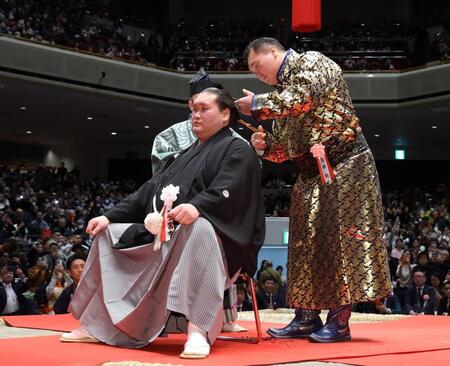 元横綱照ノ富士の伊勢ケ浜親方（左）にはさみを入れる、モンゴル衣装で登場した元横綱の白鵬翔さん