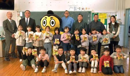 　「甘口国技館カレー」を贈呈し、言問小学校の児童と記念写真に納まる日本相撲協会広報部の西岩親方（後列左から２人目）ら＝１２日、東京都墨田区