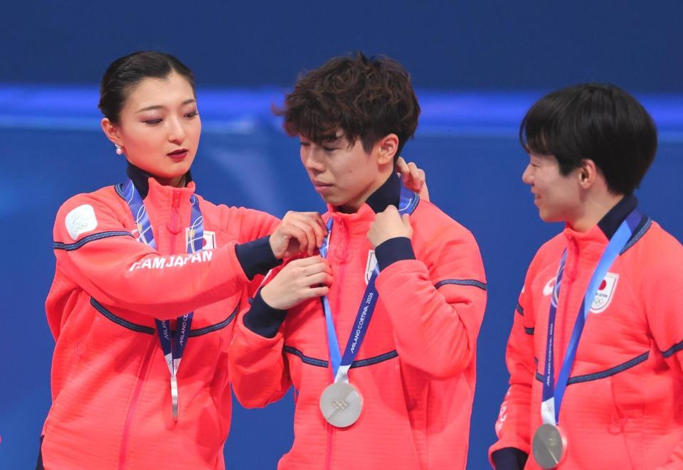 表彰台で佐藤駿㊥のメダルを整える坂本花織。右は鍵山優真