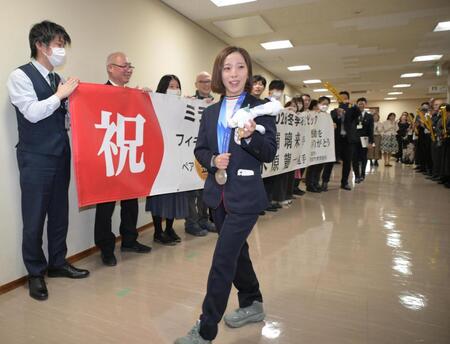 お祝いの横断幕を持つ職員に出迎えられる三浦璃来（撮影・金居みつよし）