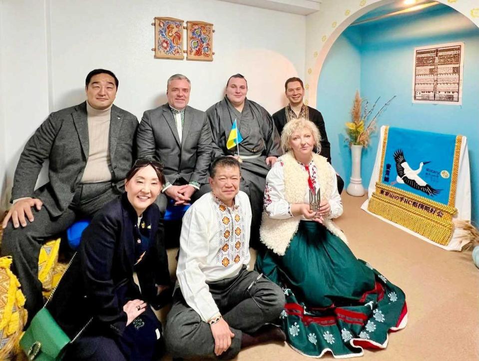 「ドミウカ」で写真に納まる安青錦（後列右から２人目）、安治川親方（同左端）、真下博志さん（前列中央）、右は展示された化粧まわし（ドミウカ提供）