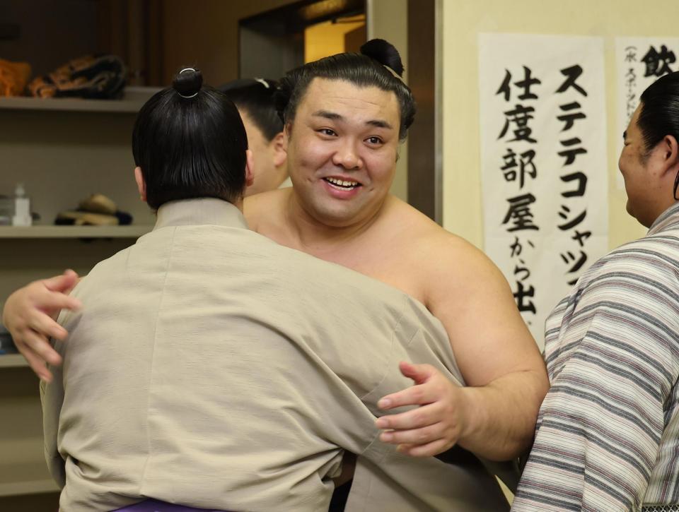 支度部屋に戻り、関係者と笑顔で抱き合う霧島