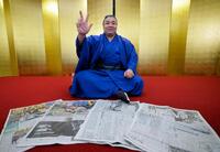 大相撲春場所で３度目の優勝を果たし、並べられた新聞を前にポーズをとる霧島