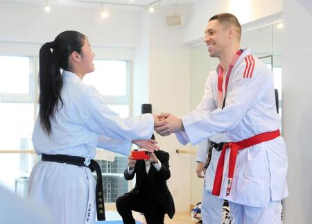 返還された東京五輪銅メダルを首からかけ、笑顔で握手するホルナさん（右）＝全日本空手道連盟＝