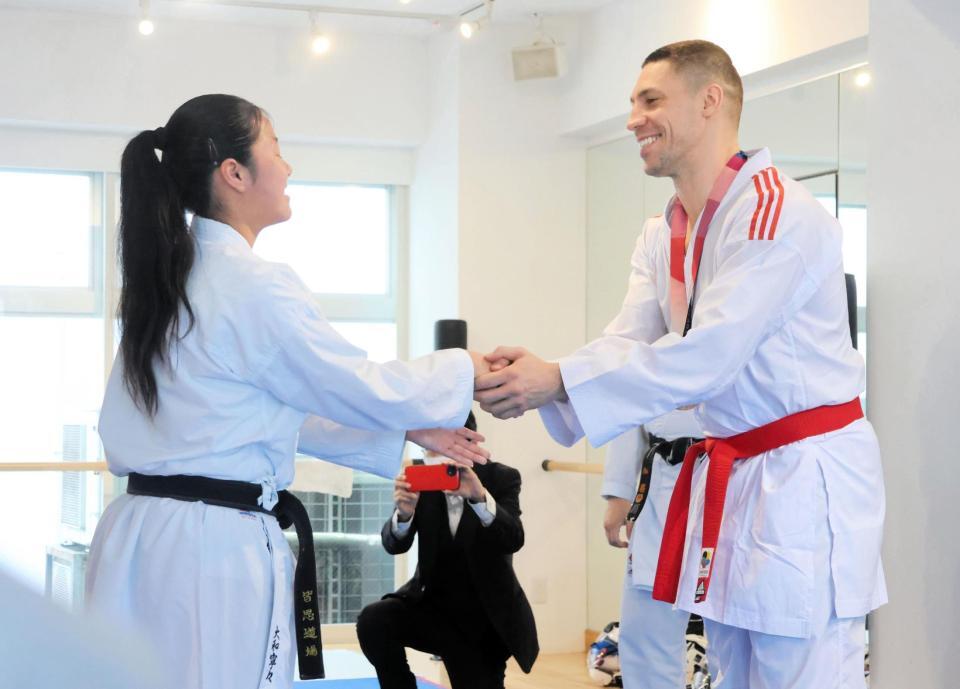 返還された東京五輪銅メダルを首からかけ、笑顔で握手するホルナさん（右）＝全日本空手道連盟＝