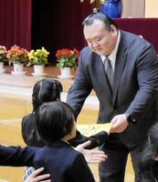 新入生にランドセルカバーを手渡す桐山親方＝都内