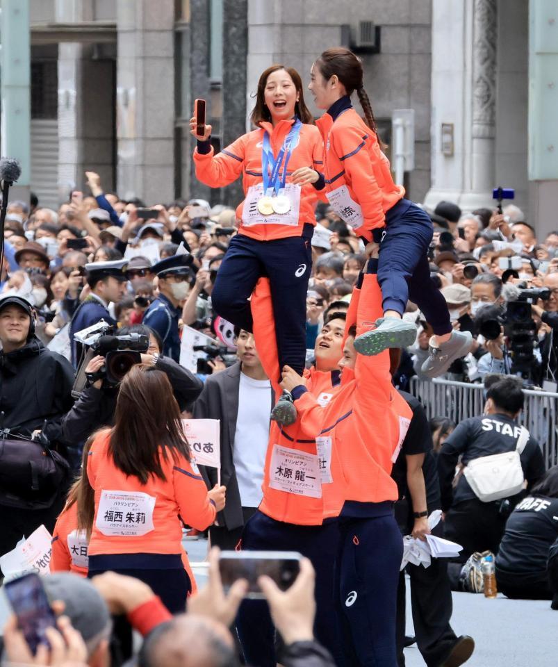 ミラノ・コルティナ冬季五輪・パラリンピックの応援感謝パレードでリフトをして写真撮影するフィギュアペア金メダルの三浦璃来、木原龍一