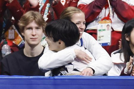 　ミラノ五輪団体男子ＳＰの演技を終え、カロリナ・コストナー・コーチ（奥）に抱きしめられる鍵山優真＝２月、ミラノ（共同）