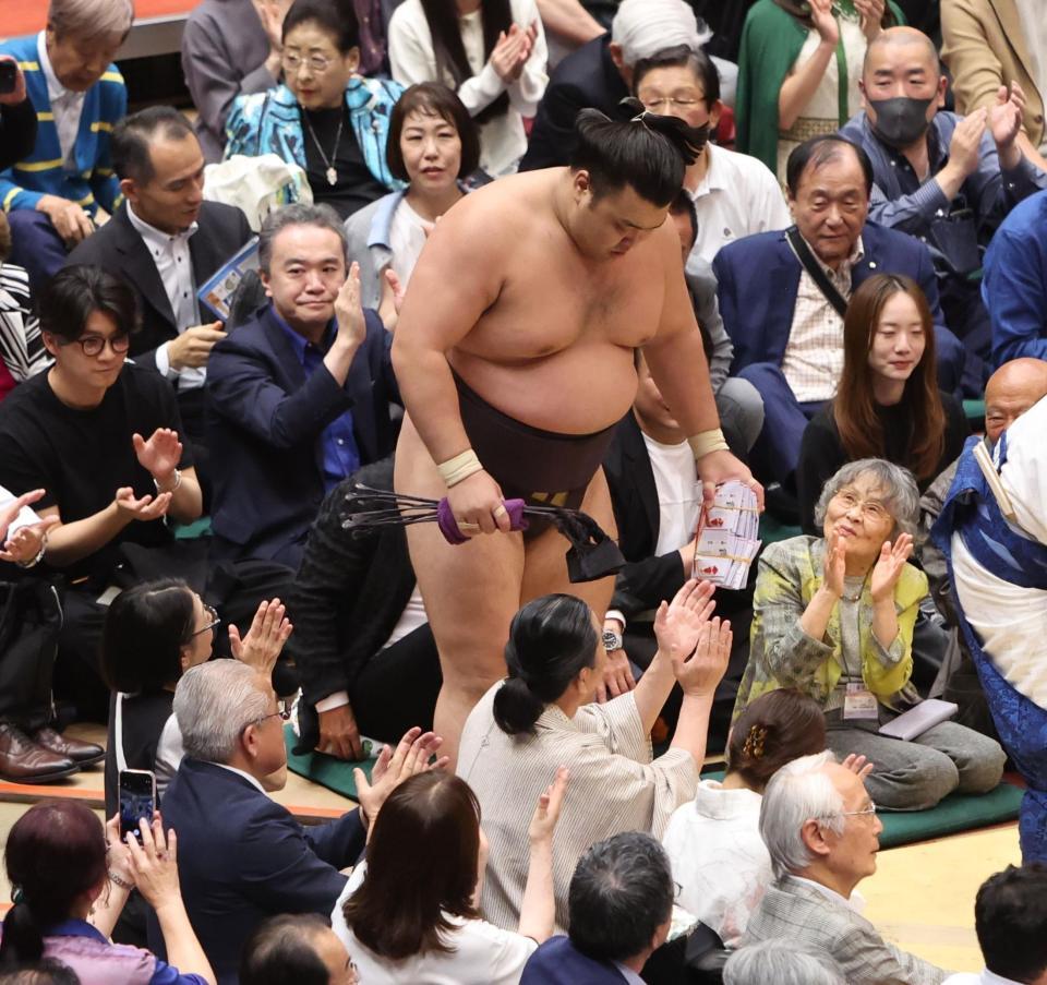 分厚い懸賞金の束を手に引き上げる霧島