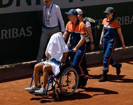 　女子シングルス１回戦の第３セットで途中棄権し、車いすで運ばれる内島萌夏（手前）＝パリ（共同）