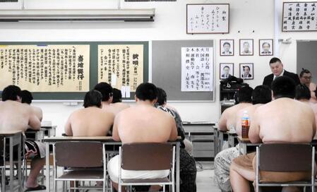 相撲甚句の枕唄と「当地興行」の歌詞を黒板に貼り、授業を進める春日山親方（右上）
