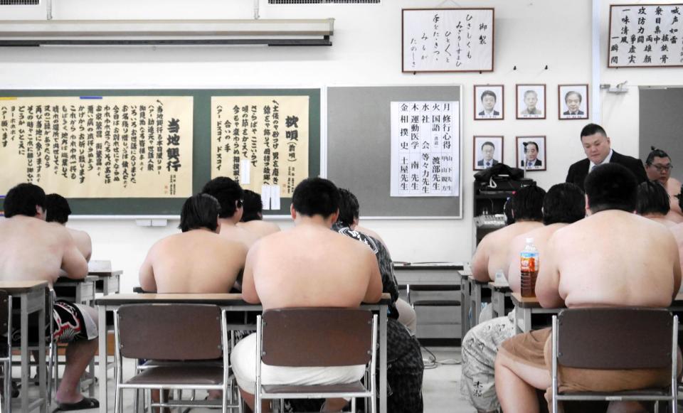 相撲甚句の枕唄と「当地興行」の歌詞を黒板に貼り、授業を進める春日山親方（右上）