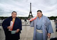 大相撲パリ公演を前に、エッフェル塔の前でフランスパンを食べる大の里（右）と豊昇龍の両横綱＝11日、パリ（共同）