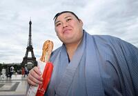 大相撲パリ公演を前に、エッフェル塔前でフランスパンを手にする横綱大の里＝11日、パリ（共同）