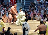 豊昇龍（手前右）に視線を投げかけながら懸賞金を鷲づかみにする伯乃富士-（撮影・立川洋一郎）