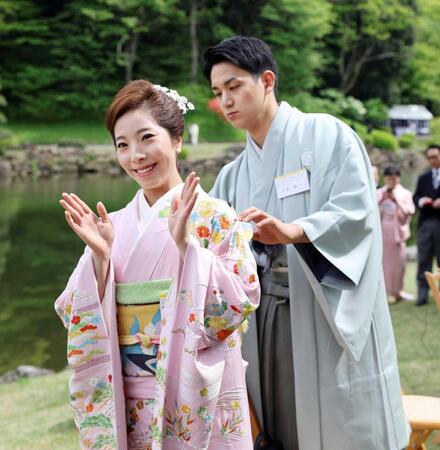春の園遊会で三浦璃来さん（左）の帯を直す木原龍一氏＝４月