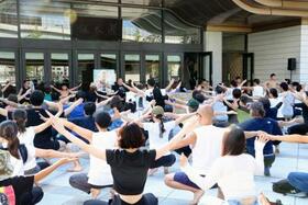 　東京・両国国技館正面前で体を動かす「夏休み！！相撲健康体操」の参加者ら＝２４日午前