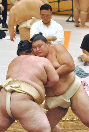 　大相撲夏巡業で熱海富士（左）と相撲を取る大の里。奥は師匠の二所ノ関親方＝茨城県つくばみらい市
