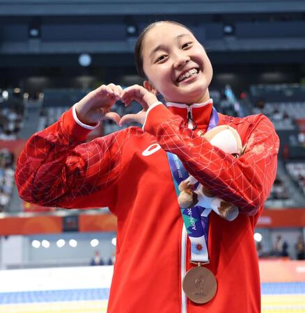 女子４００ｍ個人メドレーの表彰式を終え、カメラマンに向けてハートマークを作る成田実生（撮影・伊藤笙子）