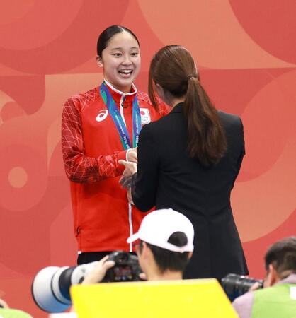 女子４００ｍ個人メドレーの表彰式で大橋悠依さん（手前）からホノホンのぬいぐるみを受け取る成田実生（撮影・伊藤笙子）