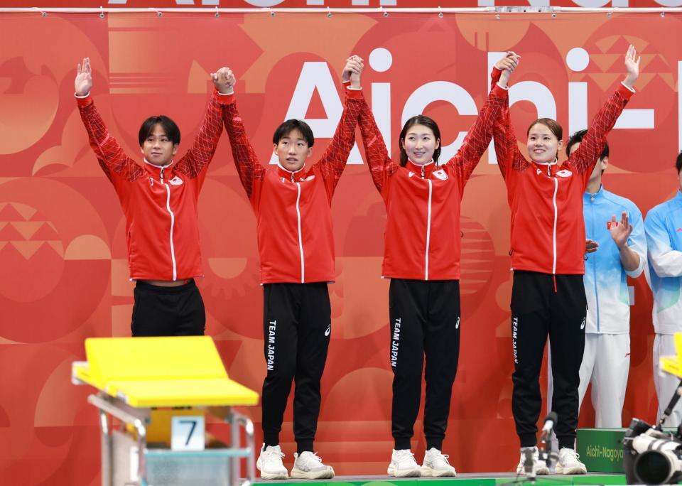 混合４００ｍメドレーリレーの表彰式で両手を掲げる（左から）竹原秀一、大橋信、池江璃花子、池本凪沙（撮影・伊藤笙子）
