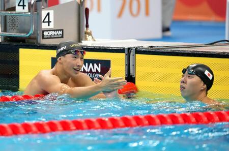 男子２００メートル平泳ぎ決勝のレースを終え、渡辺一平（右）と健闘をたたえ合う大橋信