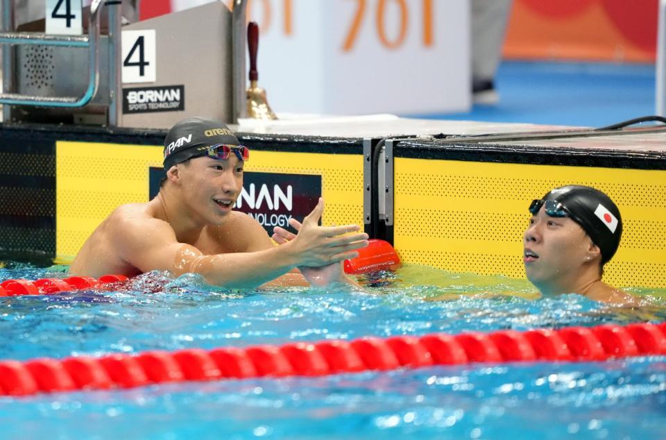 男子２００メートル平泳ぎ決勝のレースを終え、渡辺一平（右）と健闘をたたえ合う大橋信