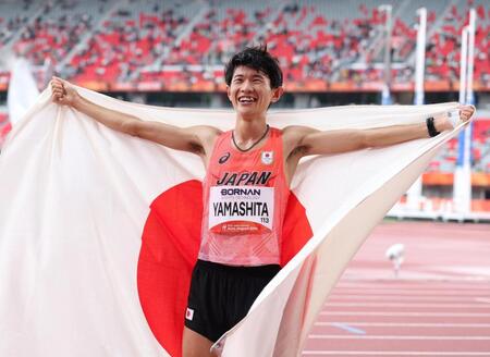 男子マラソンで金メダルを獲得し、日の丸を背に笑顔を見せる山下一貴＝愛知県名古屋市・パロマ瑞穂スタジアム（撮影・中田匡峻）