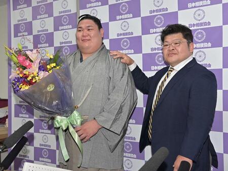 引退会見で花束をもらい押尾川親方（右）と笑顔で写真に納まる矢後（撮影・持木克友）