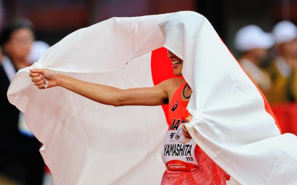男子マラソンで優勝し、日の丸を頭からかぶる山下一貴