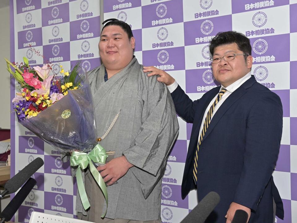 引退会見で花束をもらい押尾川親方（右）と笑顔で写真に納まる矢後（撮影・持木克友）