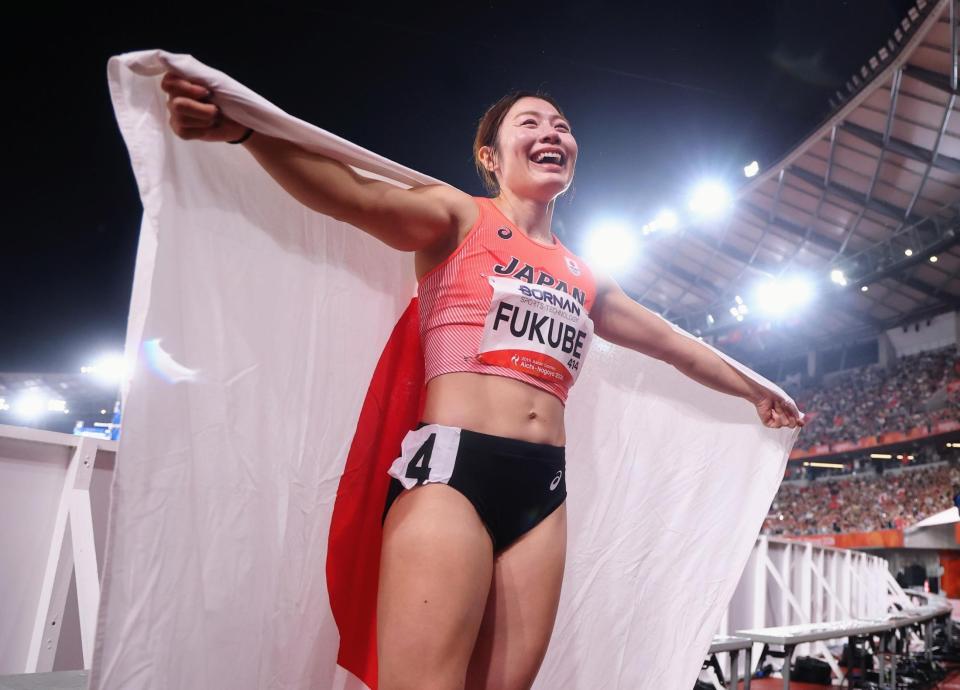 女子１００メートル障害決勝を制し、国旗を広げて笑顔を見せる福部真子