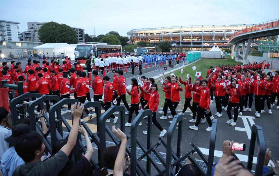 閉会式に参加するため、声援に応えながらパロマ瑞穂スタジアム（奥）へ向かう日本選手団ら