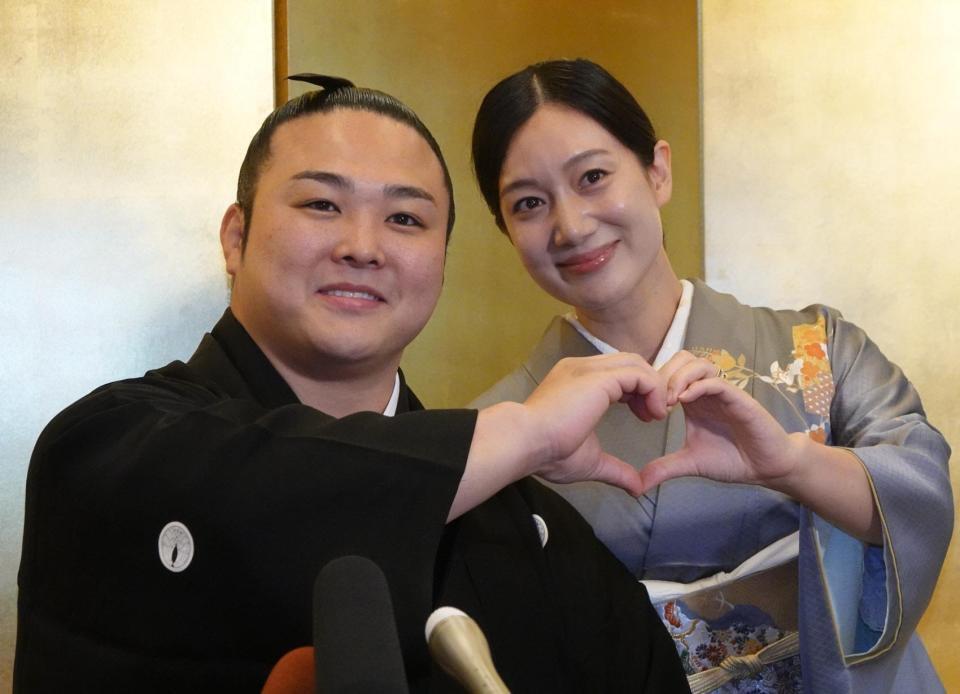 結婚報告会見でハートマークを手でつくる炎鵬（左）と妻の美希さん