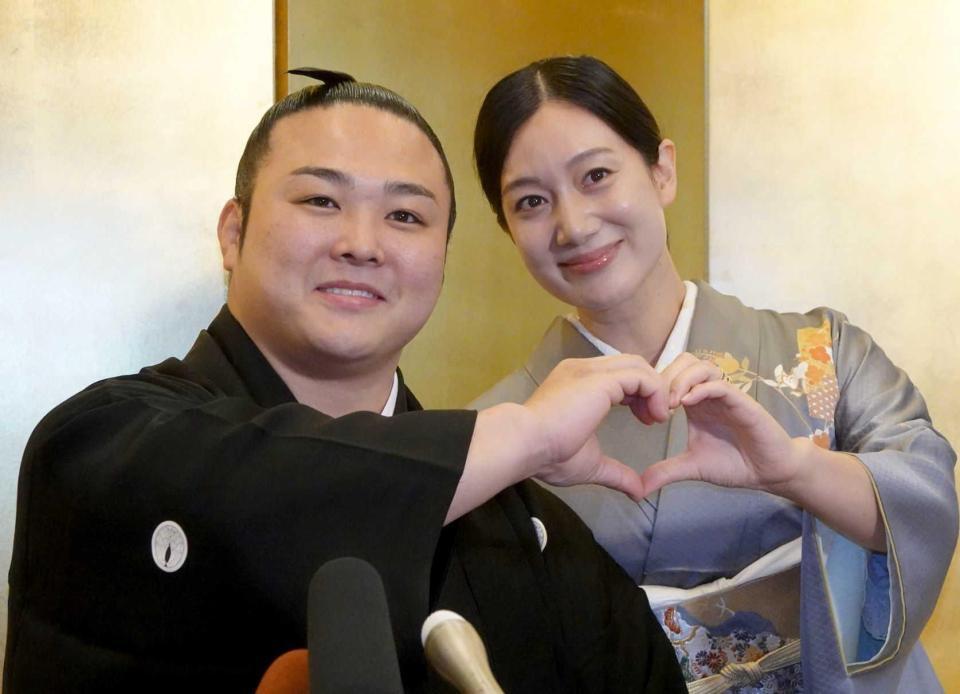 　結婚報告会見でハートマークを手でつくる炎鵬（左）と妻の美希さん