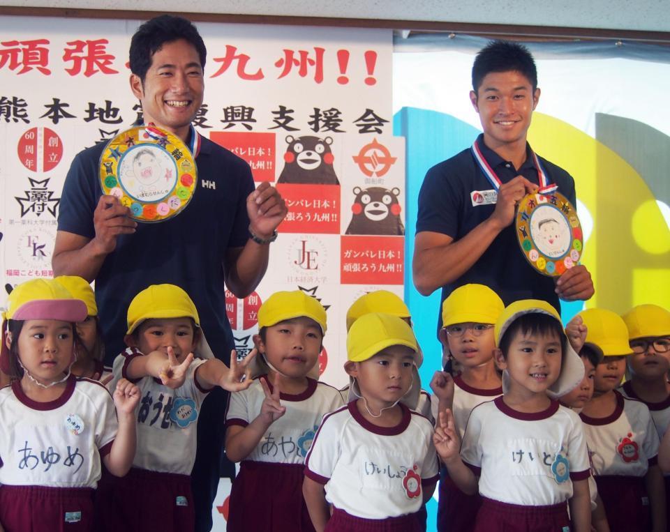 　日本経大の壮行会に出席し、熊本県御船町の被災地の園児から“金メダル”をもらって笑顔の土居（右）と今村